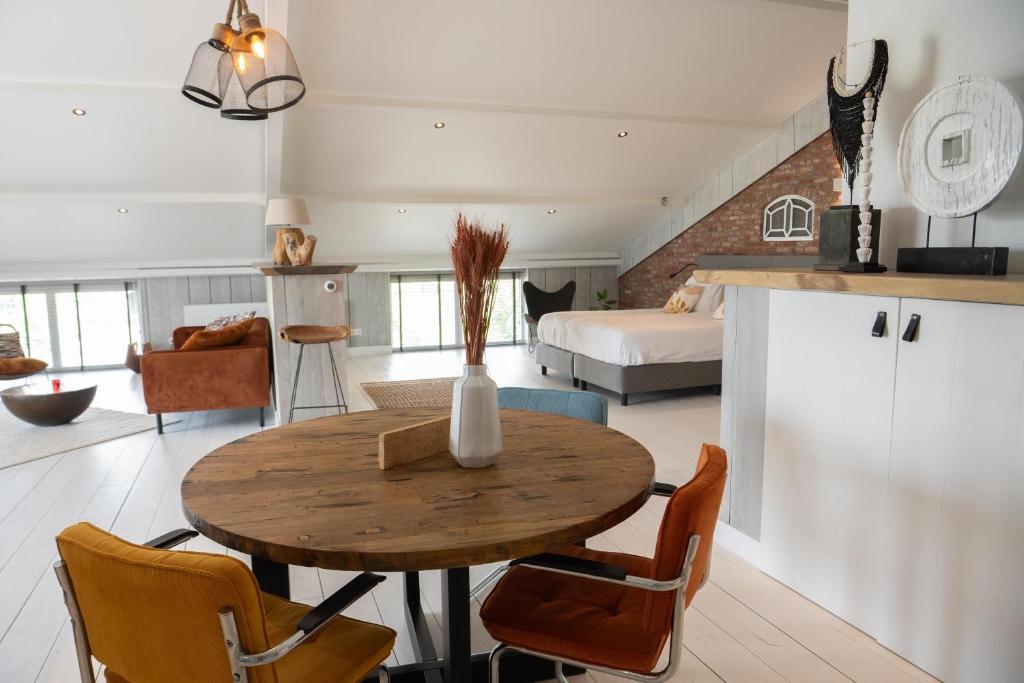 a kitchen and living room with a wooden table and chairs at Loft in de Polder in Grootschermer