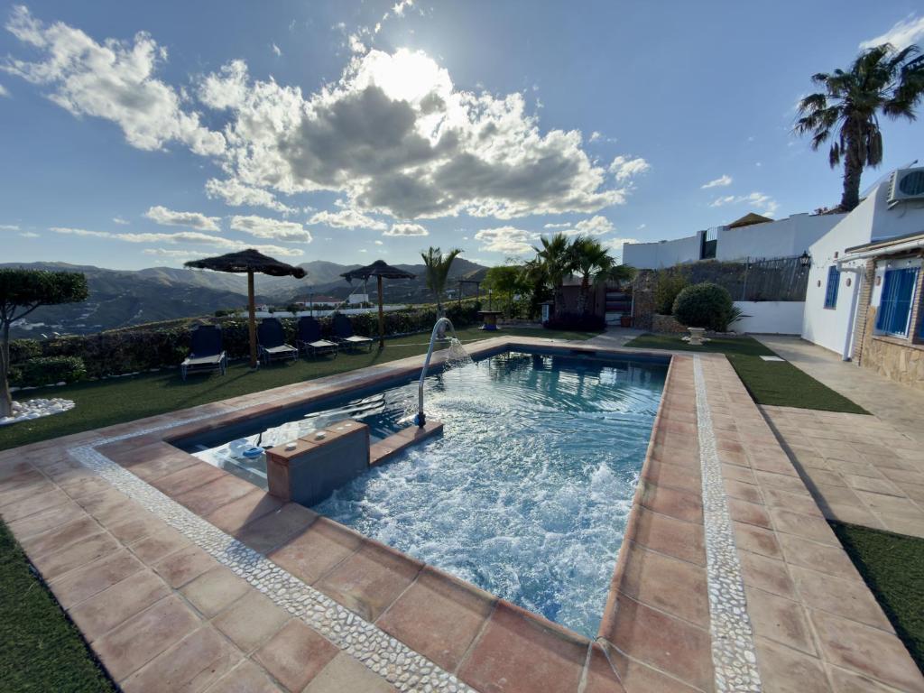 a swimming pool in a yard with chairs and umbrellas at Casa Puerta Azul By Solymar Properties in Almáchar
