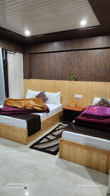 two beds in a room with wooden walls at Jai Shri Badri in Badrinath