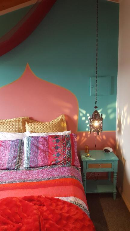 a bedroom with a red bed with a side table at The Bohemian Art Studio in Creswick