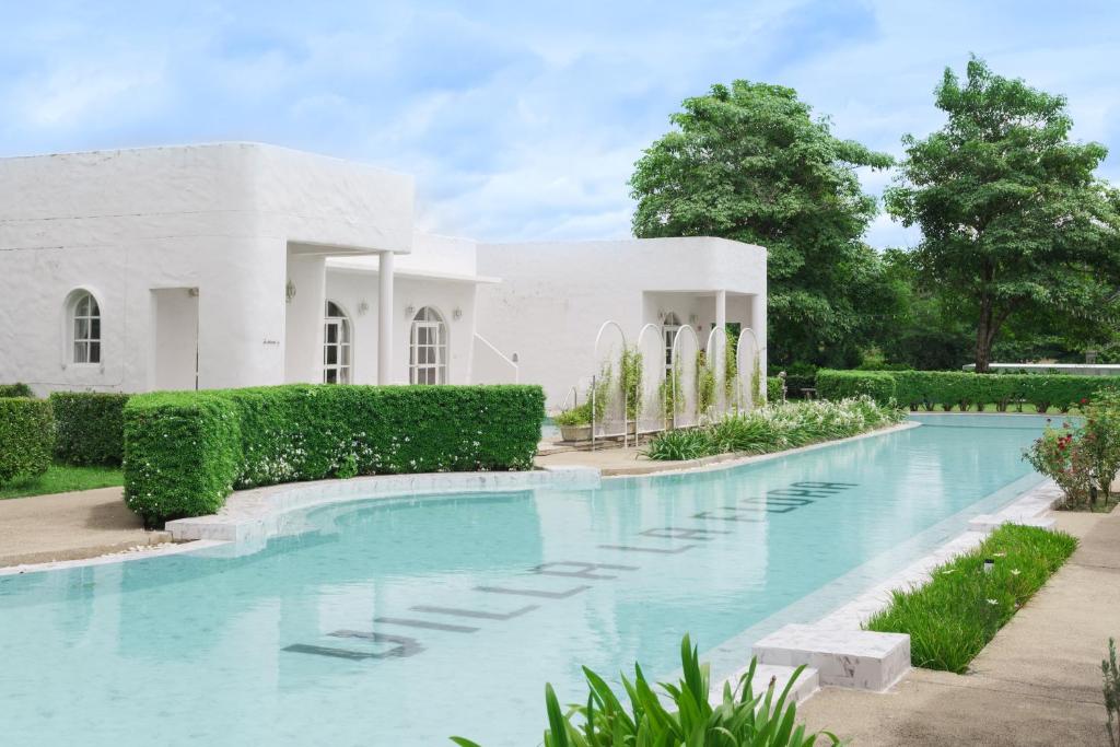 a swimming pool in front of a white house at Villa La Flora Kanchanaburi in Ban Hua Hin