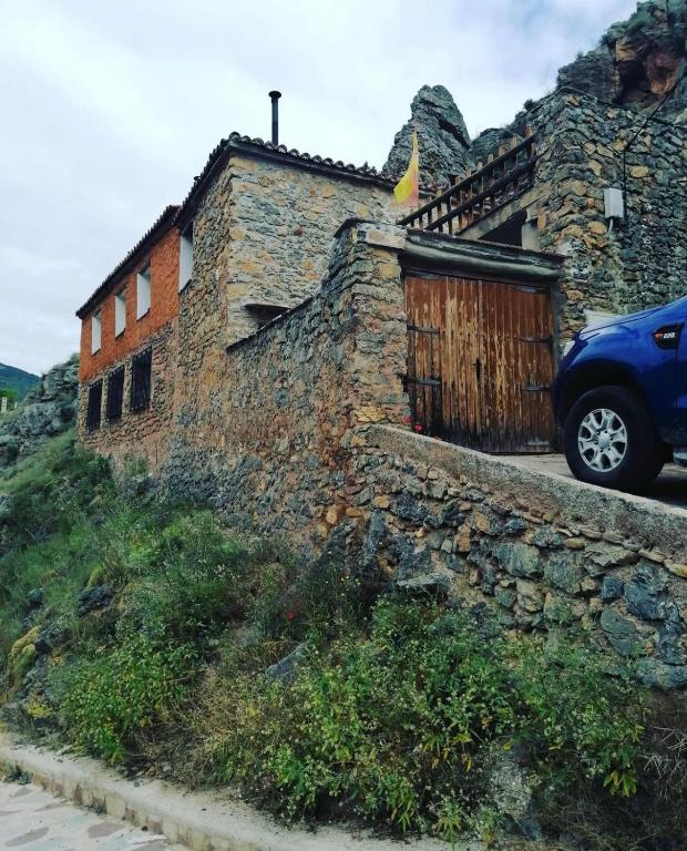 a blue car parked next to a stone building at Casa Purujosa in Purujosa