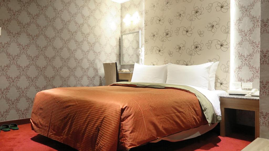 1 dormitorio con 1 cama con manta naranja en Nice Hotel en Taipéi