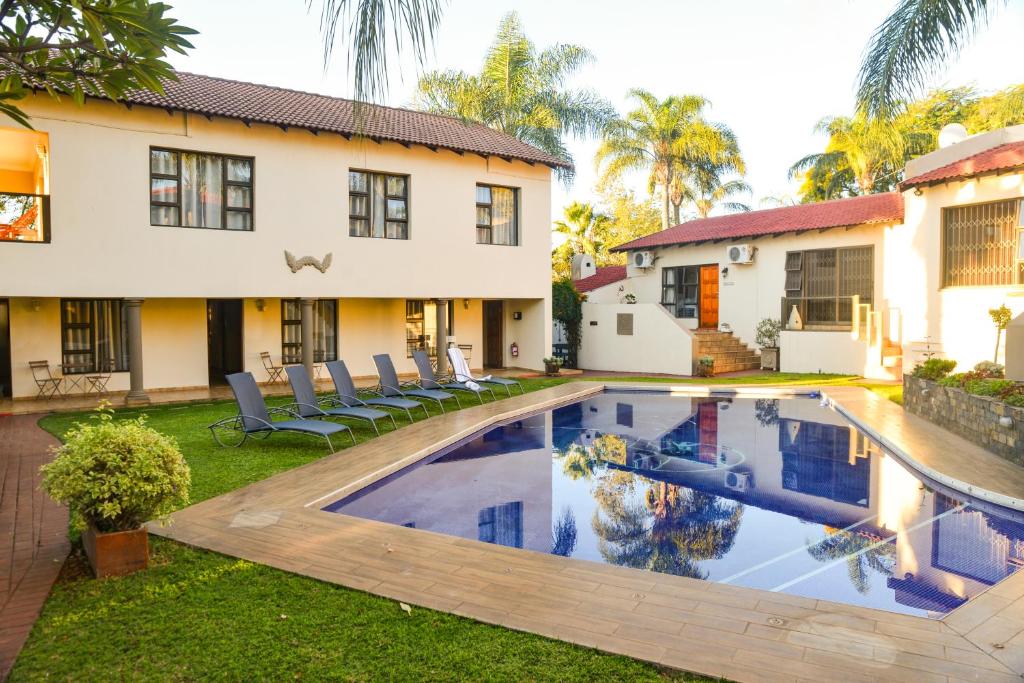 a villa with a swimming pool in front of a house at Ponciana Superior Guesthouse in Hartbeespoort
