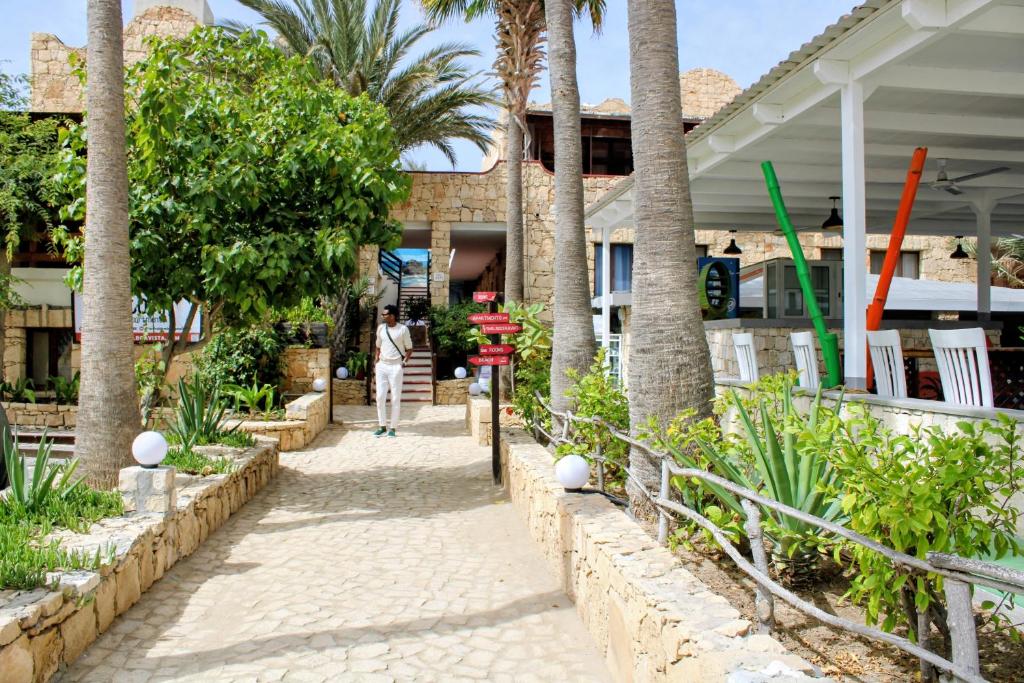 a person walking down a sidewalk in front of a building at Estoril Hotel - Apartments in Sal Rei