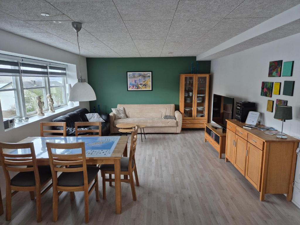 a living room with a table and chairs and a couch at Cosy apartment in Norðskála in Norðskáli
