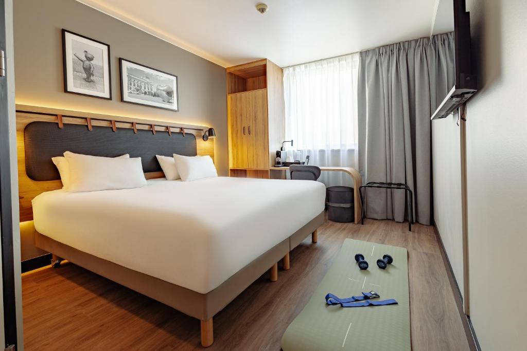 a hotel room with a large bed and shoes on the floor at Campanile PRIME - Lodz in Łódź