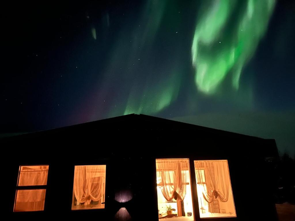 a view of the northern lights from a house with windows at Cozy Cabin Iceland in Reynivellir