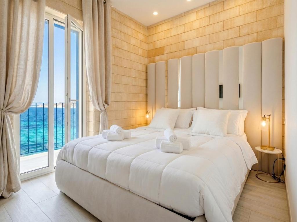 a large white bed in a room with a large window at Terra | 2-Bedroom with Shared Kitchen & Balcony – Seafront Location in Polignano a Mare