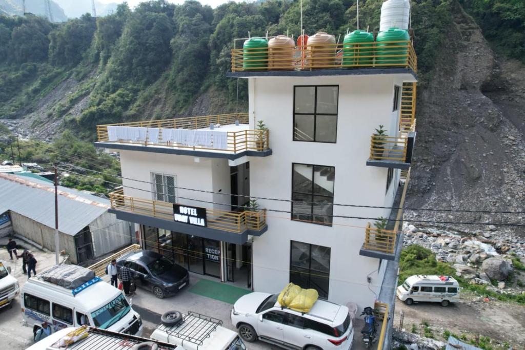 a white building with cars parked in front of it at Hotel Uday Villa in Kharsālī