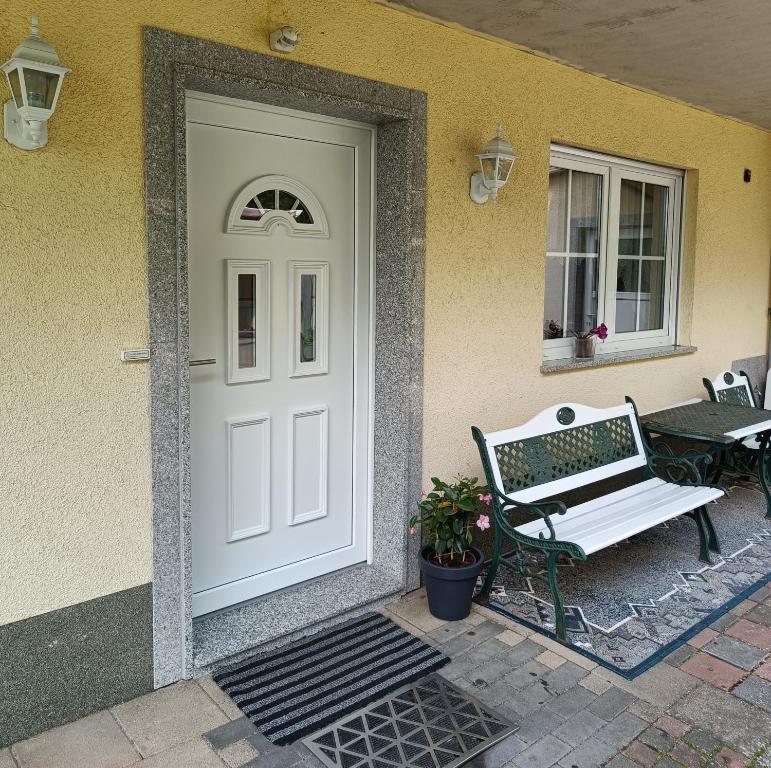 a white door of a house with a bench at Ferienwohnung mit Terrasse Ettringen in Ettringen