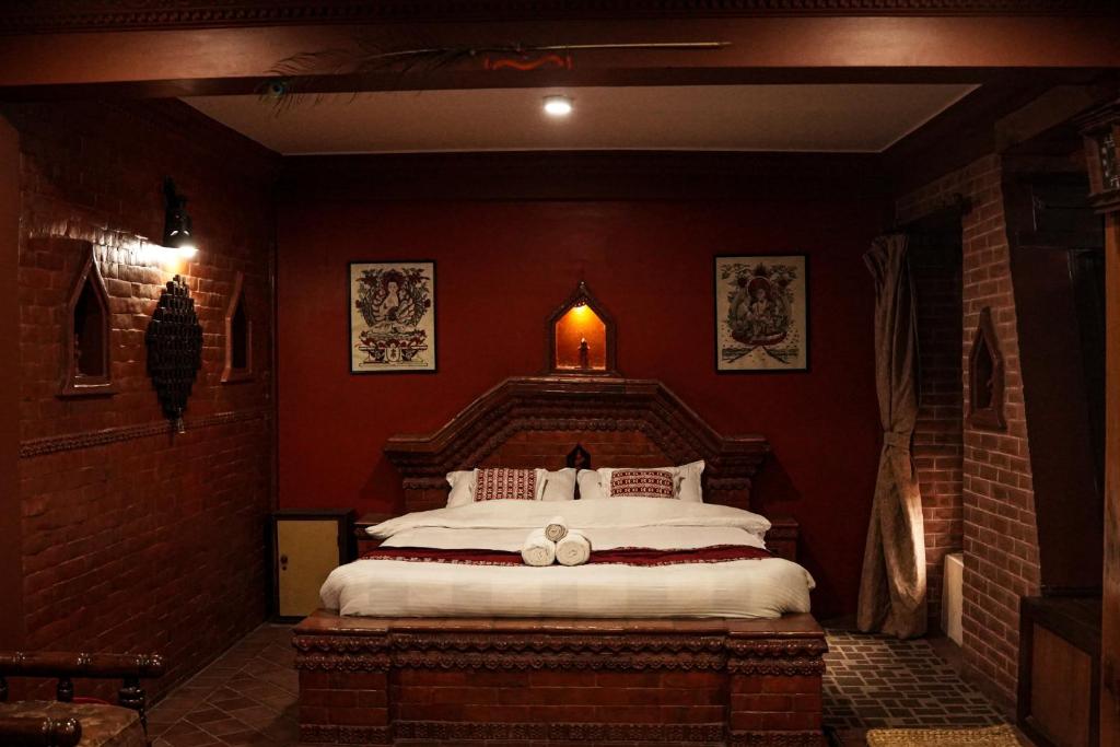 a bedroom with a large bed with red walls at Hotel Terracotta in Bhaktapur