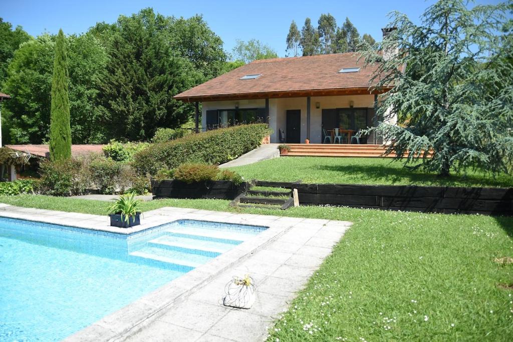 a house with a swimming pool in front of a yard at Villa La Pinpa in Bárcena de Cicero