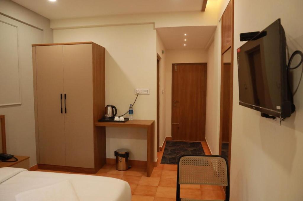 a room with a bed and a tv and a cabinet at Arma Residency Kannur in Kannur