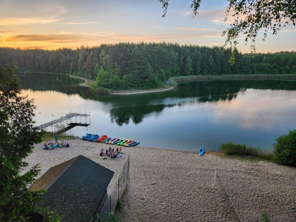 a group of people sitting on the shore of a lake at Domki Dębrzyno in Juszki