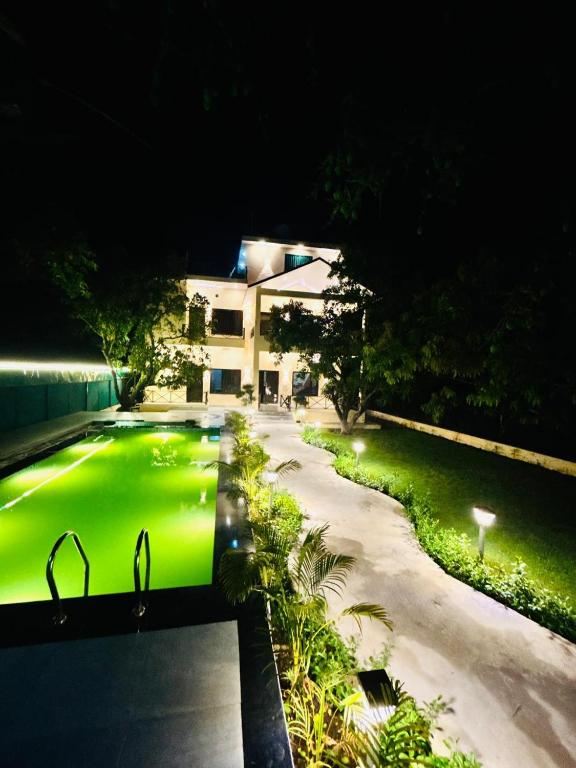 a view of a house at night with a green lawn at Corbett Sun Shine in Rāmnagar