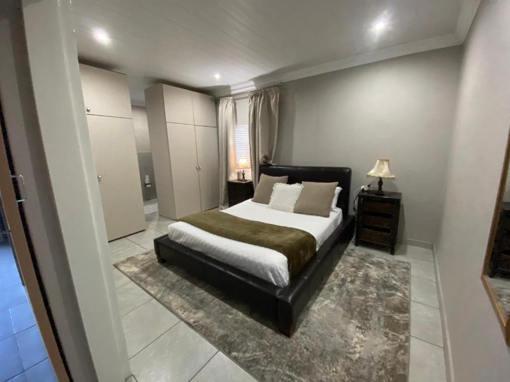a bedroom with a bed and a table and a lamp at Slaapnet Guesthouse Long Stay Accommodation Wilkoppies in Klerksdorp