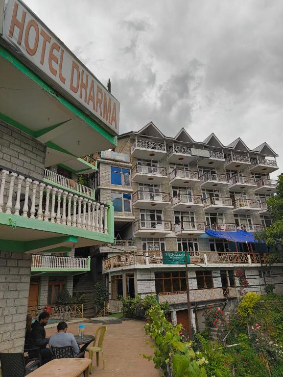 a hotel with people sitting at tables in front of it at Pachamama Hotels- Vashisht in Manāli