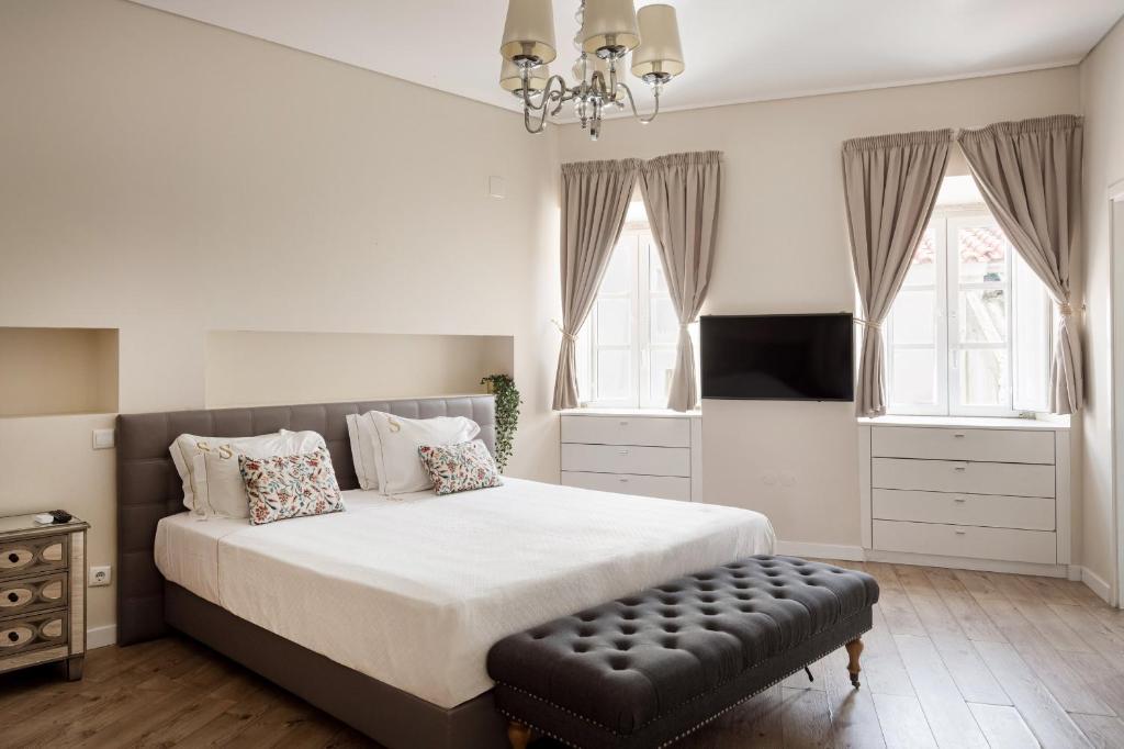 a bedroom with a large bed with a black ottoman at Suites Guest House in Cascais