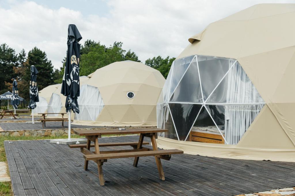 a row of tents with a table and an umbrella at Glamping Prague Louka in Prague