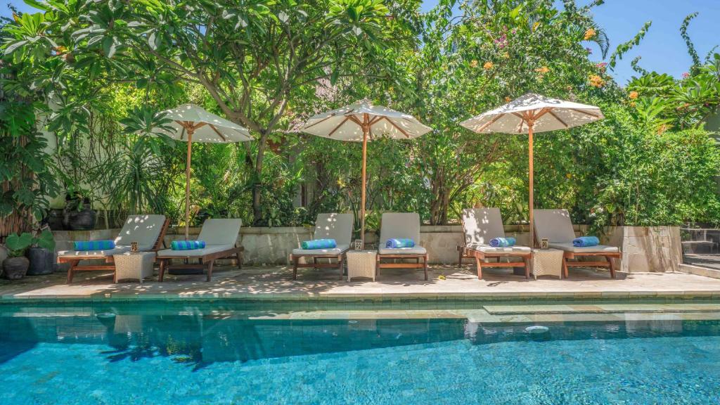 a group of chairs and umbrellas next to a swimming pool at Bale Sampan Boutique Bungalows in Gili Trawangan