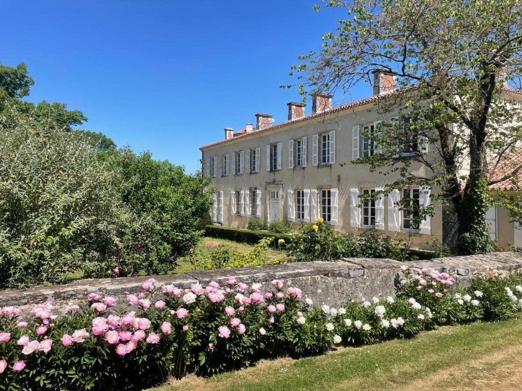 a large house with pink roses in front of it at Logis de la Jordronnière, Chambre d hôtes in Sigournais