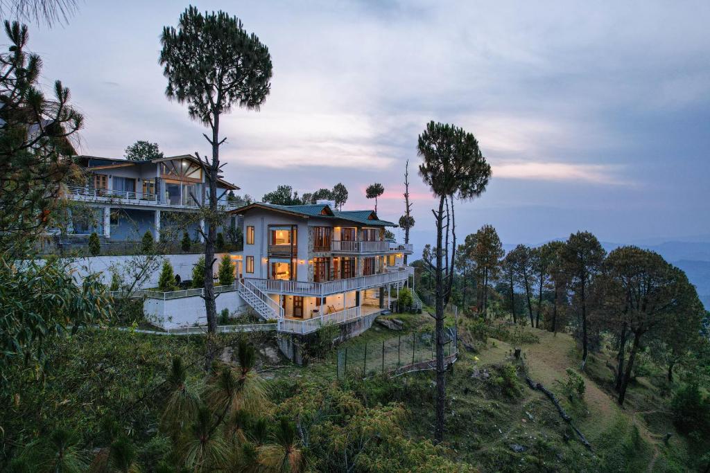 a house on top of a hill with trees at SaffronStays Brookside Estate in Rānīkhet