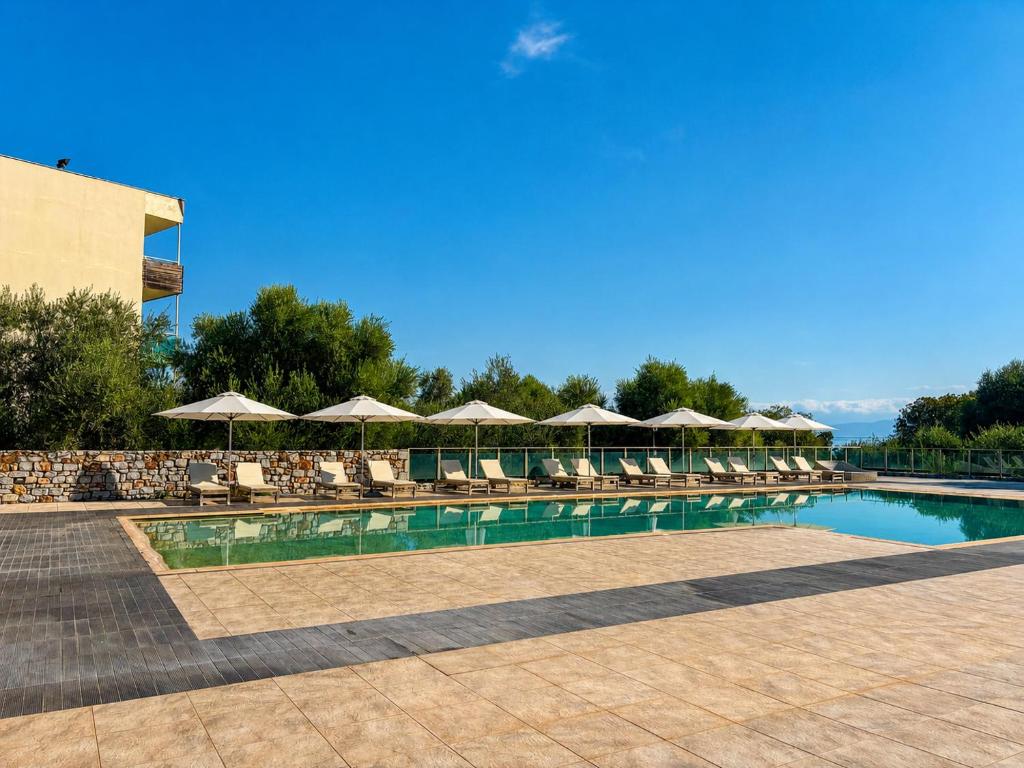 a swimming pool with chairs and umbrellas at Belle Helene Hotel by GHH in Vathi
