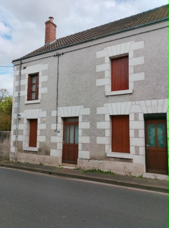 a white brick house with brown doors on a street at Maisonnette de village in Mosnes