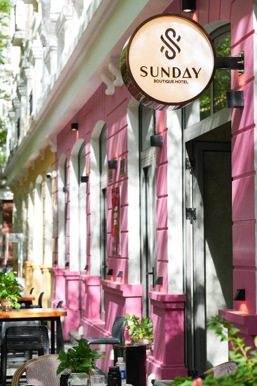 a sign on the side of a pink building at Sunday Boutique Hotel in Phú Quốc