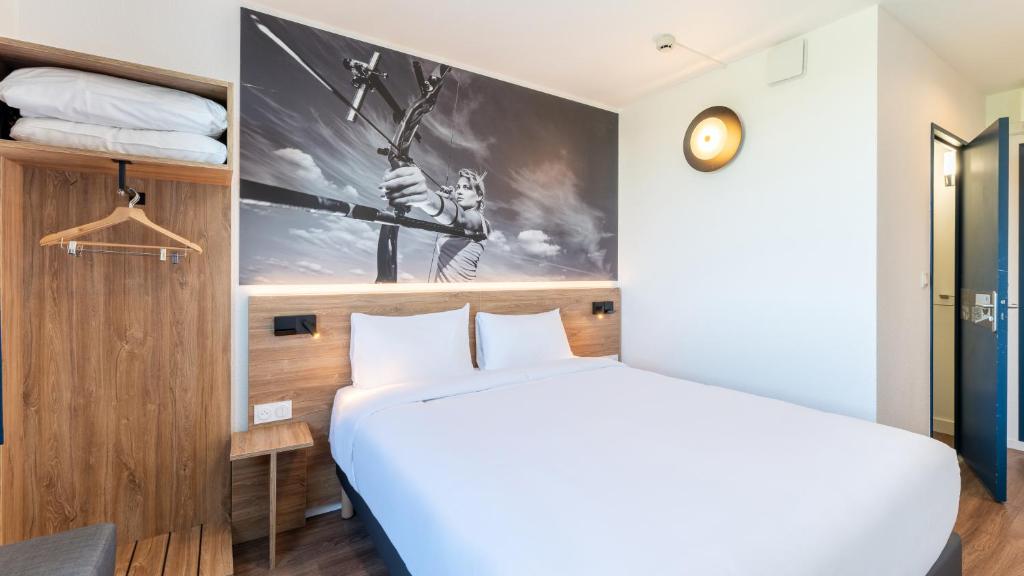 a bedroom with a bed and a wall with a poster at Campanile PRIME - Lyon Meyzieu Eurexpo Arena Stadium in Meyzieu