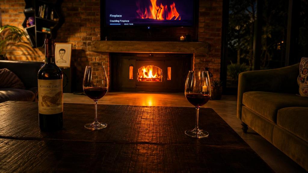 two glasses of wine on a table with a fireplace at Alimandi Villa in Klapmuts