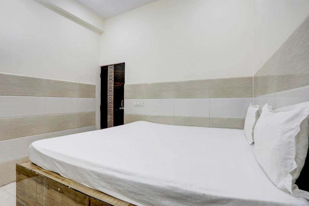 a bedroom with a white bed with a wooden headboard at Hotel O The Starlight in Ghaziabad