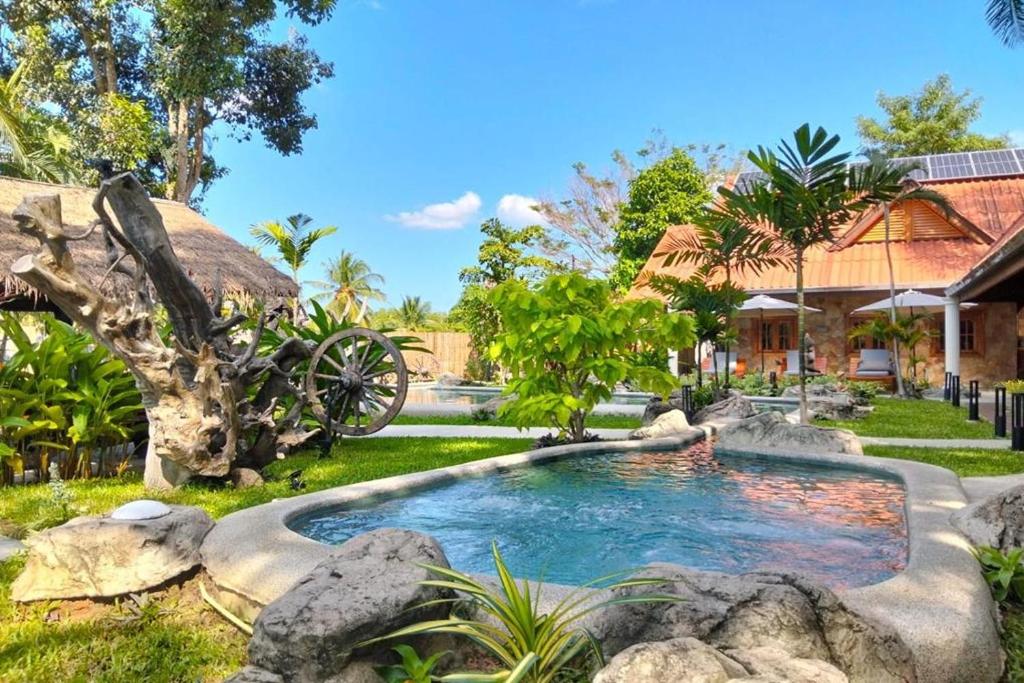 a pool in a yard with rocks and a cannon at Varaya Resort in Ban Kraek