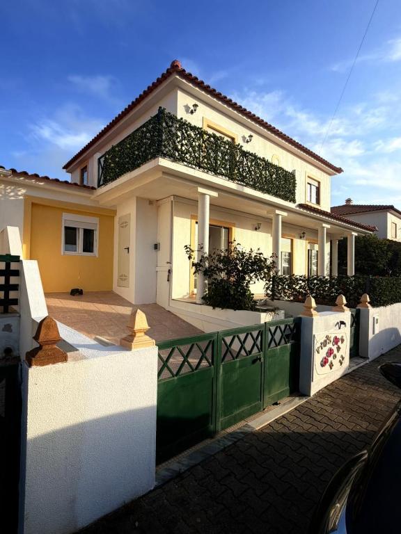 a white house with a green fence in front of it at Vio's Home in Serra de El-Rei