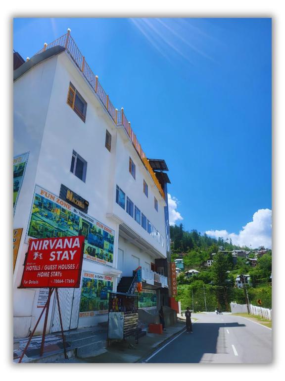 a white building with a sign in front of it at Nirvana Stay & Gaming Zone in Bhadarwāh