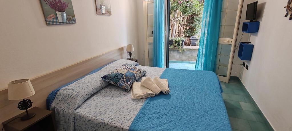 a bedroom with a bed with a blue comforter at MAREE SOL RESIDENCE Camere e Appartamenti in Torre San Giovanni Ugento