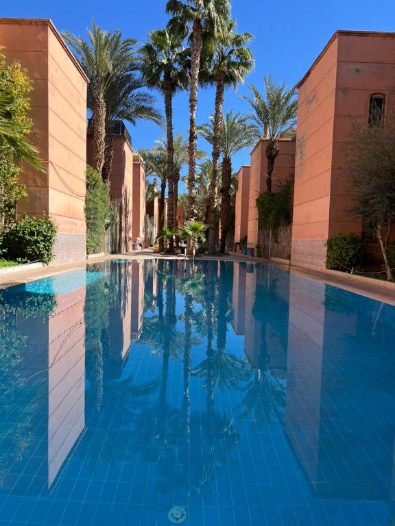 a swimming pool with palm trees and blue water at Riad Anbar in Marrakesh