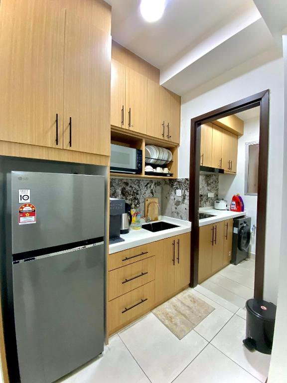 a kitchen with wooden cabinets and a stainless steel refrigerator at K Avenue by FRHome, 2 bedroom apartment within 5 min to KKIA airport in Kota Kinabalu