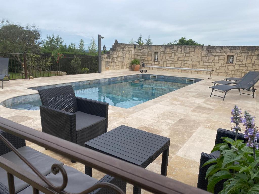 a swimming pool with two chairs and a table at chambre d'hotes les cigales in Comps