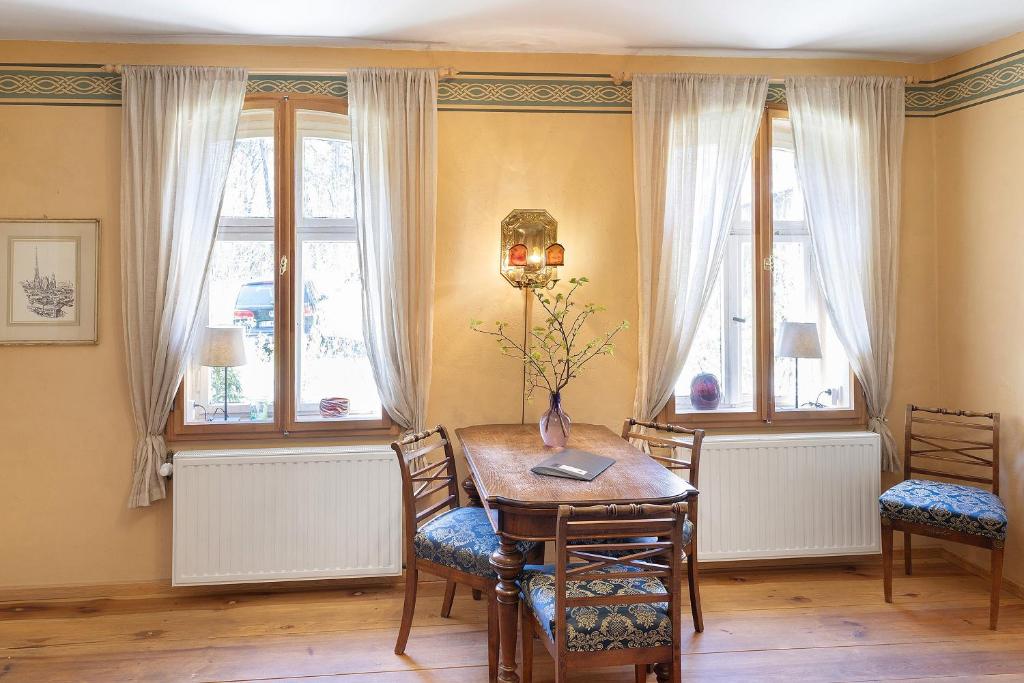 a dining room with a table and chairs and windows at Ferienwohnung am Roten Schloss in Glashütte