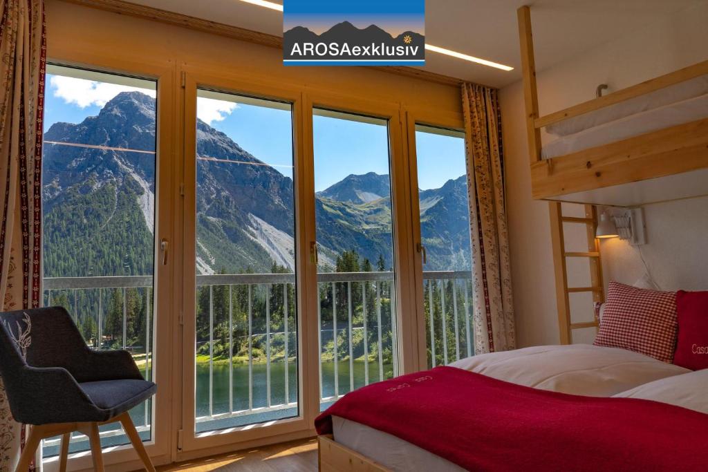 a bedroom with a large window with a mountain view at Casa Calmea in Arosa