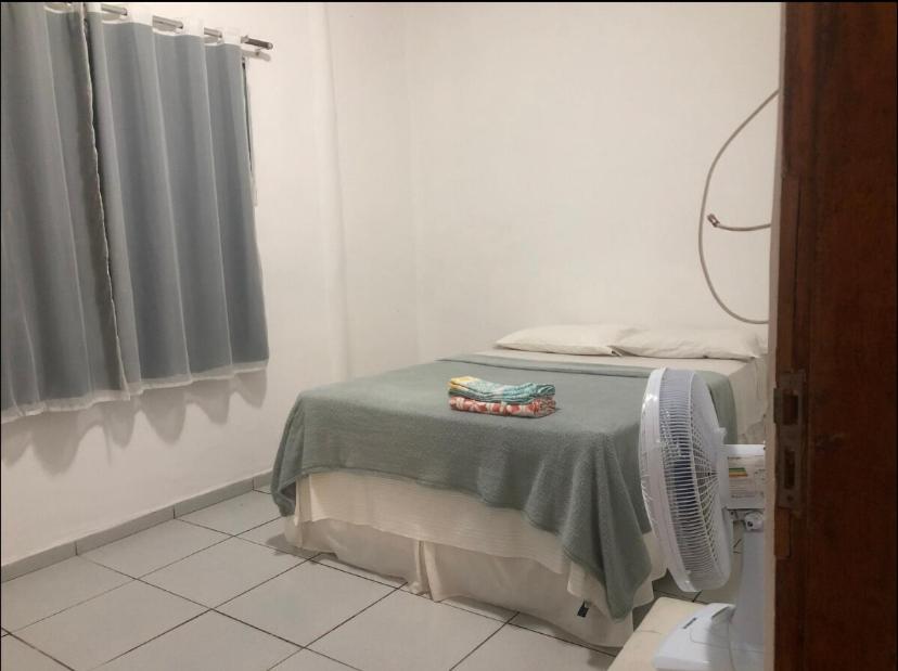 a room with a bed with a fan and a window at Lar sossego Itabuna in Itabuna