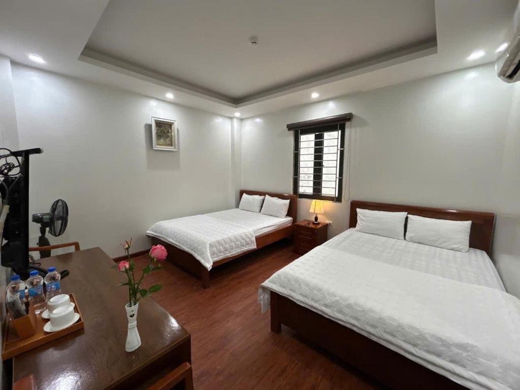a bedroom with two beds and a table with flowers at Sam Son Golden Dream Hotel in Sầm Sơn
