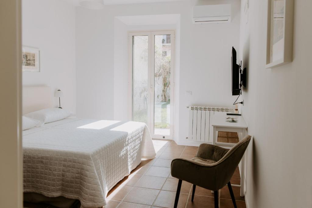 a white bedroom with a bed and a chair at Casa Vacanze Bottasso 68 in Terracina