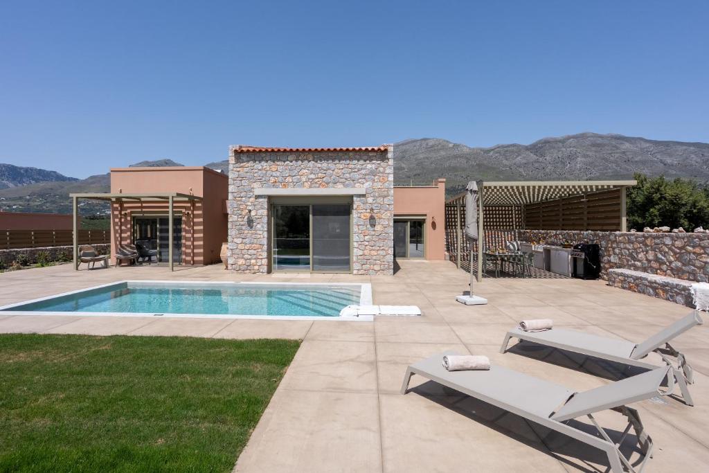 a villa with a swimming pool and mountains in the background at Vedema Homes in Lefkogeia