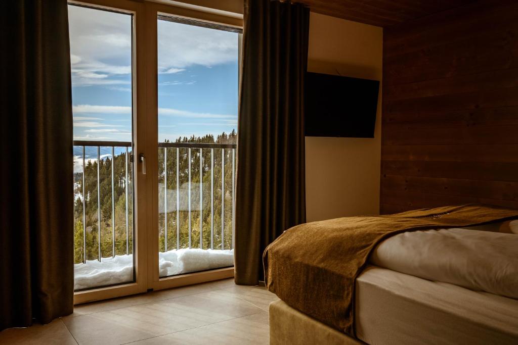 a bedroom with a bed and a large glass window at Hotel Panorama Kope in Šmartno pri Slovenj Gradcu
