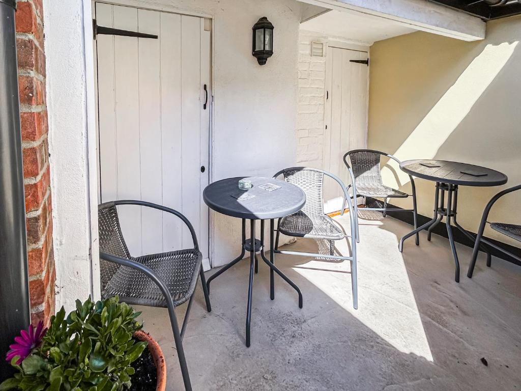 two tables and chairs on a balcony with a door at Corner Cottage in Saxmundham
