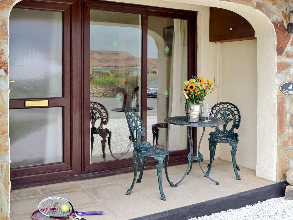 a patio with a table and chairs and a glass door at Chynoweth in Saint Merryn