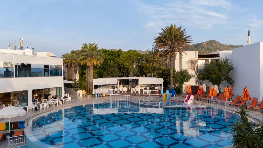 a large swimming pool with chairs and umbrellas next to a building at SOLANA By YELKEN in Turgutreis